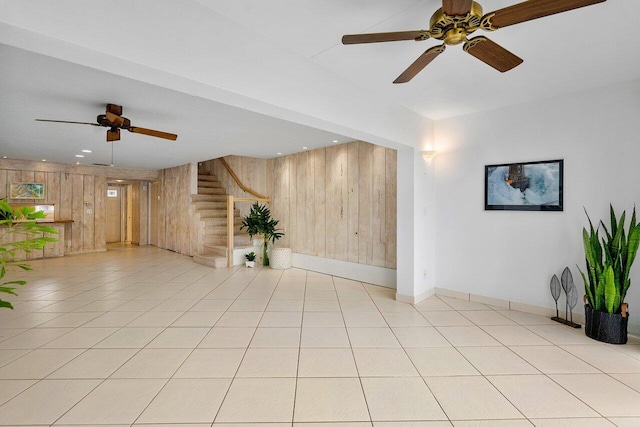 empty room with ceiling fan, light tile patterned floors, and wooden walls