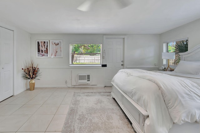 bedroom featuring multiple windows, light tile flooring, ceiling fan, and a wall mounted AC