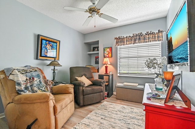 office area featuring built in shelves, a textured ceiling, light hardwood / wood-style floors, and ceiling fan