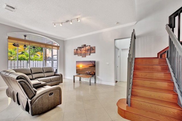 living room featuring rail lighting, a textured ceiling, light tile floors, and ornamental molding