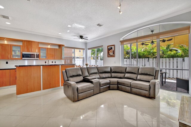 tiled living room featuring sink, crown molding, ceiling fan, and a textured ceiling