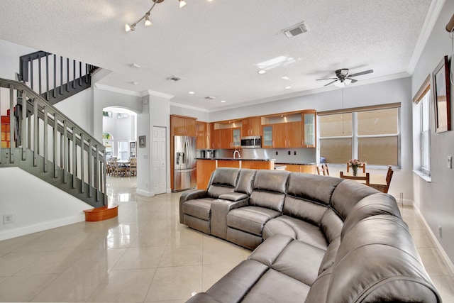 living room featuring a textured ceiling, ceiling fan, light tile flooring, and ornamental molding