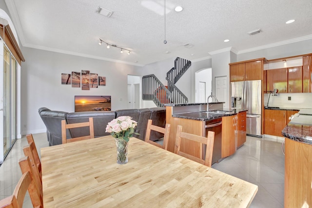 dining area with light tile floors, a textured ceiling, sink, crown molding, and rail lighting