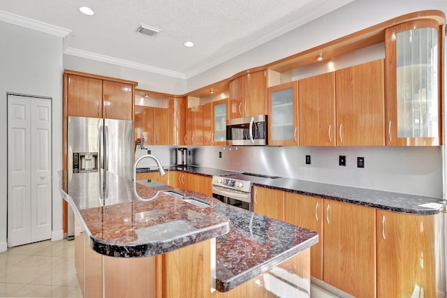 kitchen featuring appliances with stainless steel finishes, dark stone countertops, a kitchen island with sink, and light tile floors