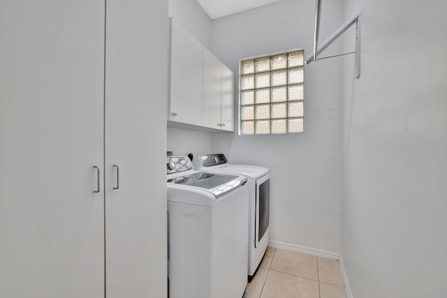 washroom featuring washing machine and dryer, cabinets, and light tile floors