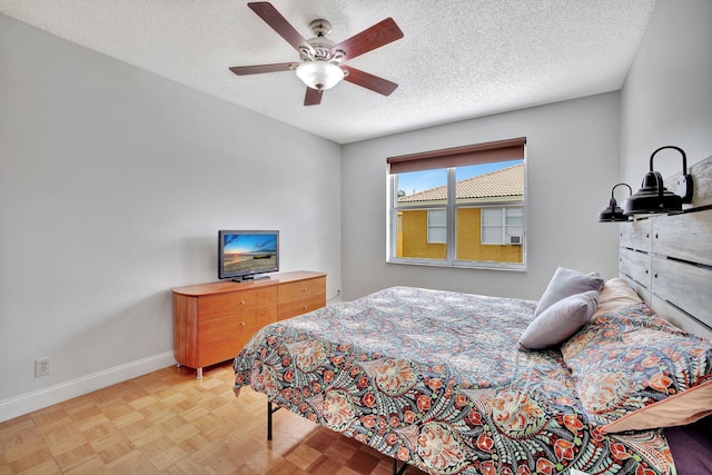 bedroom featuring ceiling fan, light parquet floors, and a textured ceiling