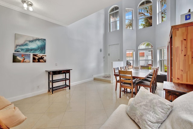 tiled dining space with crown molding, a towering ceiling, and a textured ceiling