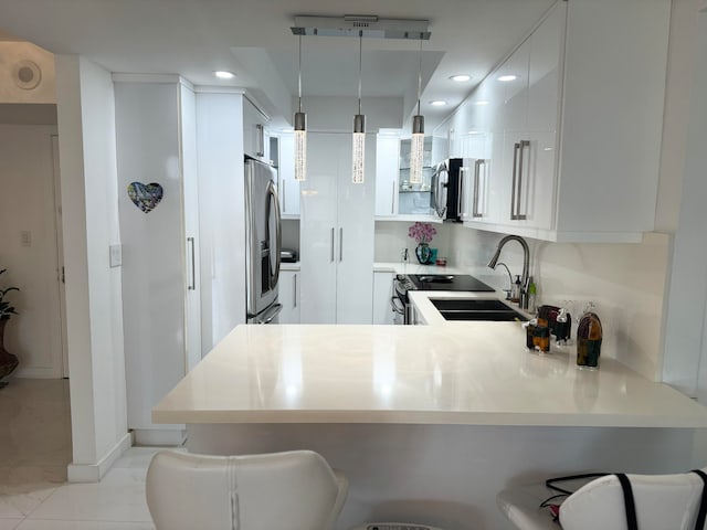 kitchen featuring pendant lighting, a kitchen breakfast bar, kitchen peninsula, and white cabinets