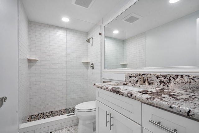 bathroom with tiled shower, vanity, and toilet