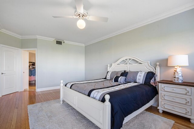 bedroom with hardwood / wood-style flooring, ceiling fan, and crown molding