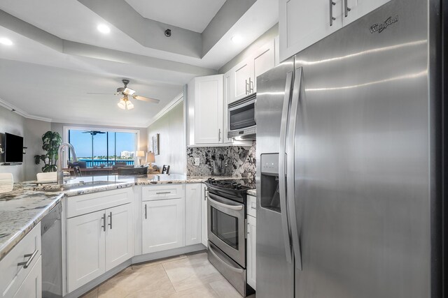 kitchen with kitchen peninsula, appliances with stainless steel finishes, backsplash, white cabinetry, and a breakfast bar area