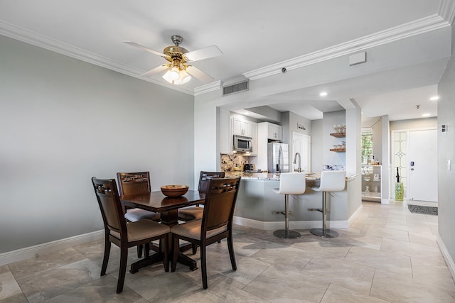 tiled dining area featuring ceiling fan, ornamental molding, and sink