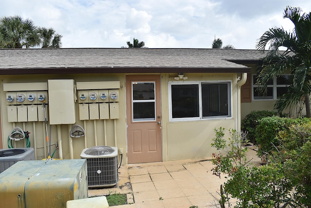 view of exterior entry with a patio and central AC unit