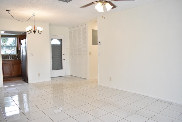 tiled empty room with sink, a textured ceiling, electric panel, and ceiling fan with notable chandelier