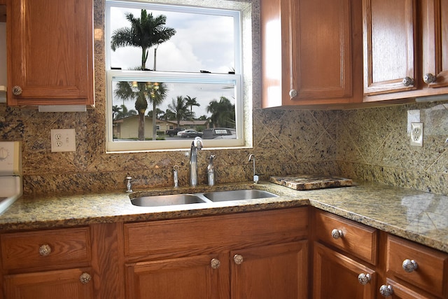 kitchen featuring sink, light stone countertops, and decorative backsplash