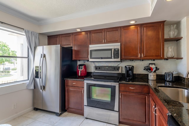 kitchen with decorative backsplash, appliances with stainless steel finishes, dark stone counters, ornamental molding, and sink