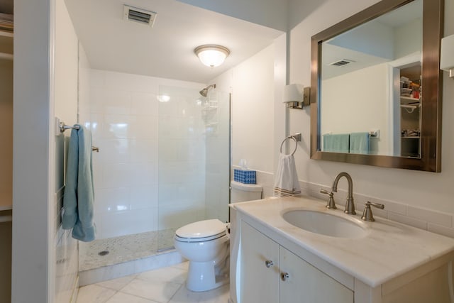 bathroom with vanity, toilet, and a tile shower