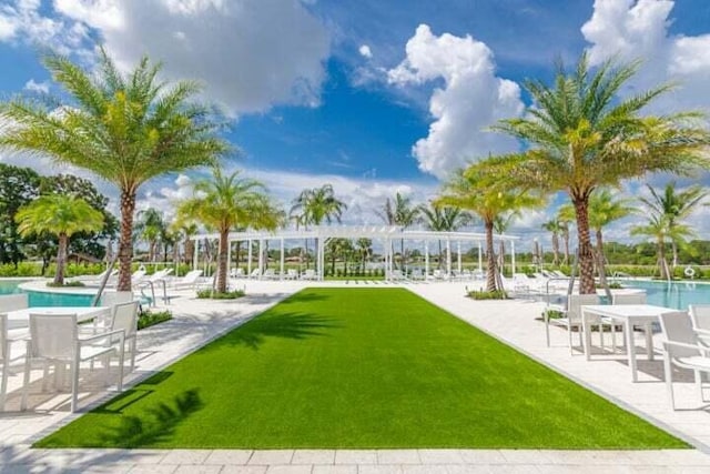 view of community with a yard, a pool, and a patio area