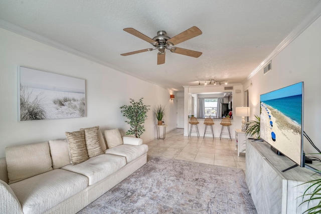 tiled living room featuring a textured ceiling, ceiling fan, and ornamental molding