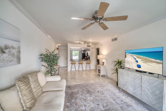 tiled living room featuring a textured ceiling, ceiling fan, and crown molding