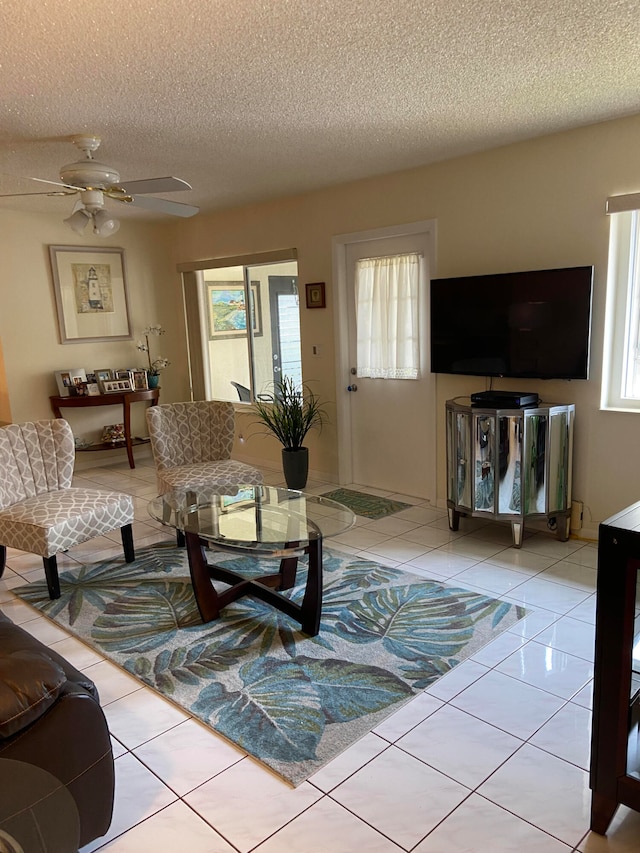 tiled living room with ceiling fan and a textured ceiling