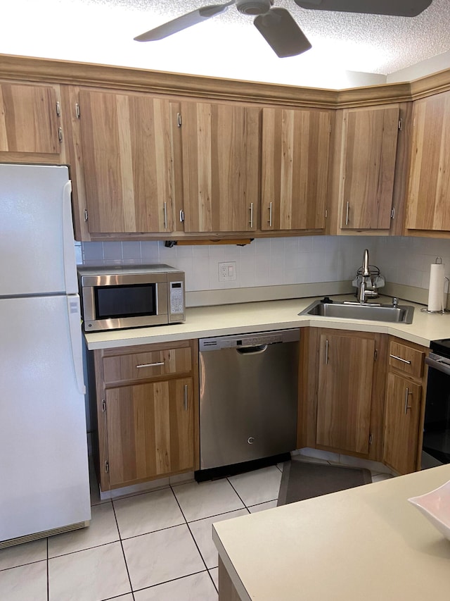 kitchen featuring ceiling fan, light tile patterned floors, sink, a textured ceiling, and appliances with stainless steel finishes