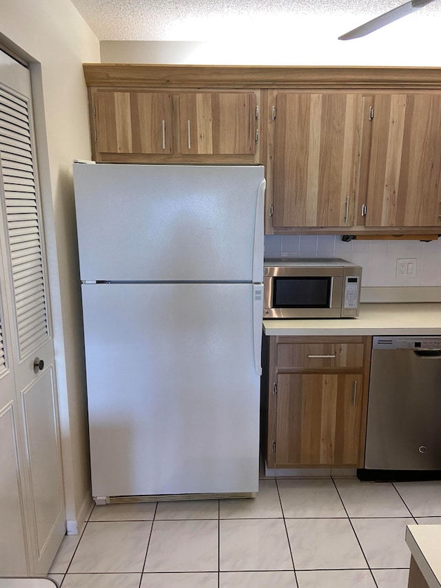 kitchen featuring a textured ceiling, stainless steel appliances, light tile patterned floors, and tasteful backsplash