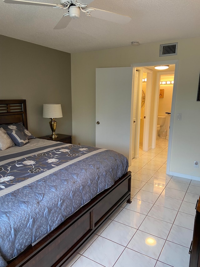 bedroom featuring ensuite bath, ceiling fan, light tile patterned floors, and a textured ceiling