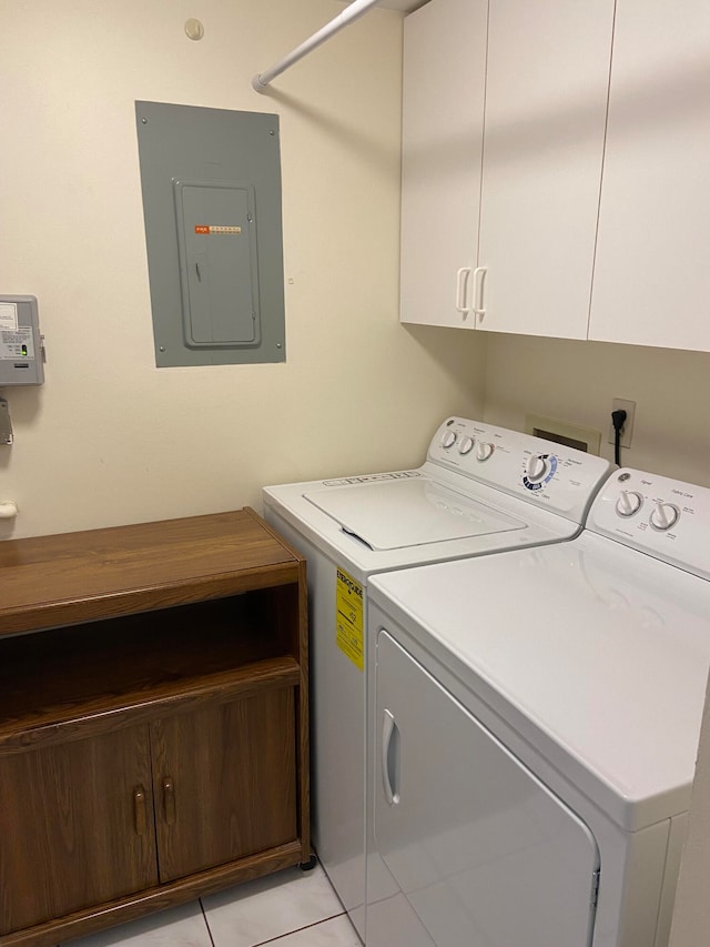 clothes washing area featuring washer and clothes dryer, light tile patterned flooring, electric panel, and cabinets