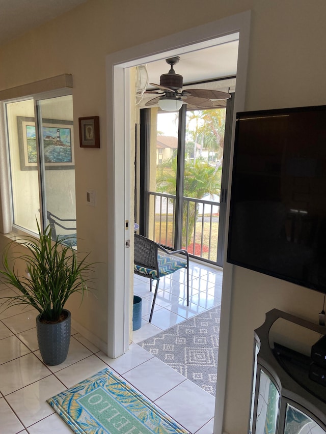 doorway featuring ceiling fan, light tile patterned floors, and a wealth of natural light