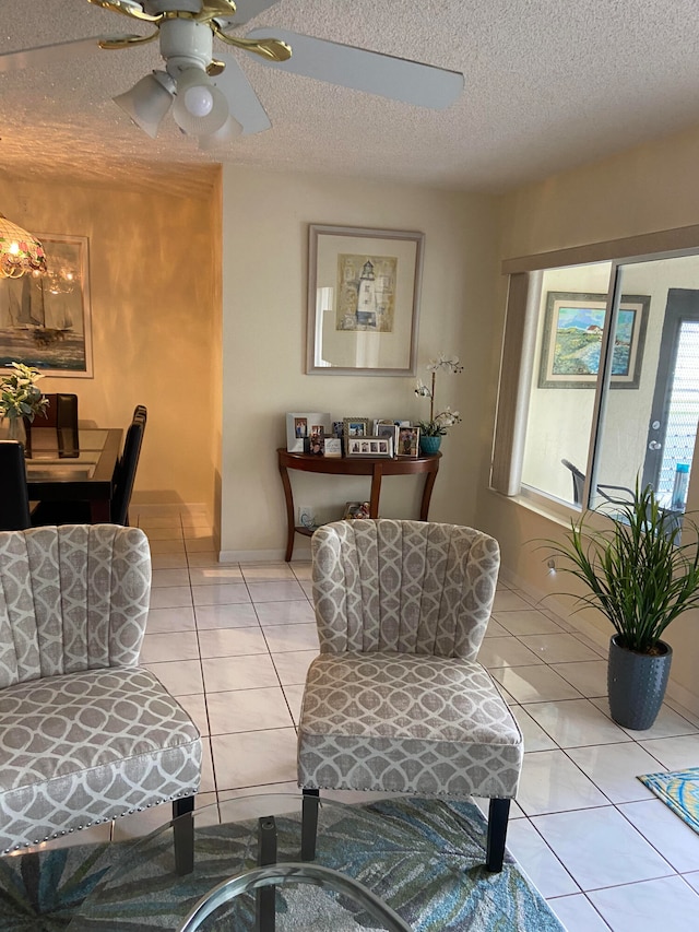 living area with ceiling fan, light tile patterned floors, and a textured ceiling