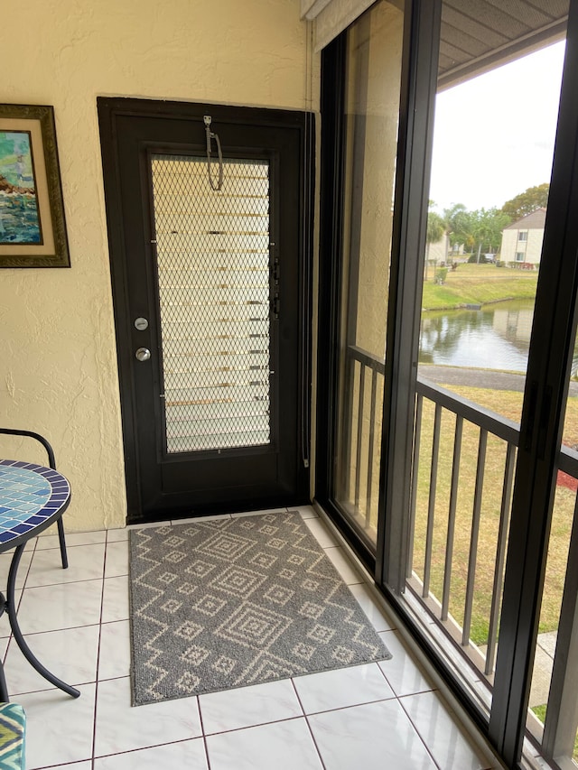 entryway featuring a wealth of natural light, a water view, and light tile patterned floors