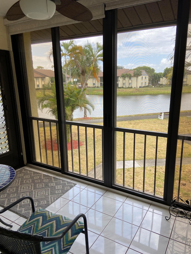 sunroom featuring a water view and ceiling fan