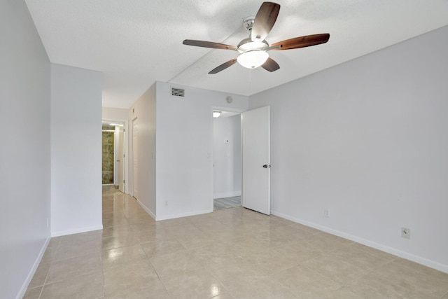 tiled empty room featuring a textured ceiling and ceiling fan