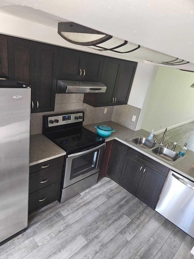 kitchen with light hardwood / wood-style flooring, appliances with stainless steel finishes, sink, tasteful backsplash, and exhaust hood