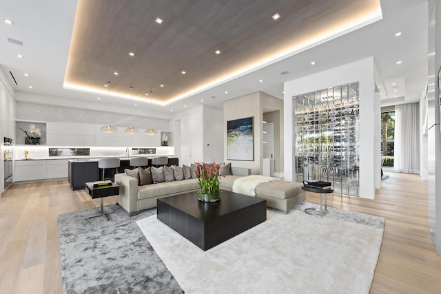 living room featuring built in features, light wood-type flooring, and a tray ceiling