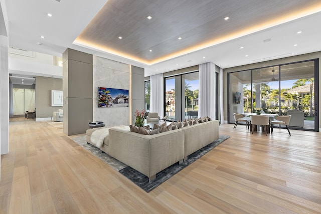 living room featuring light wood-type flooring and a tray ceiling