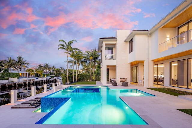 pool at dusk with a patio area