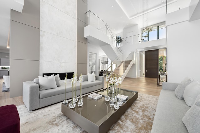 living room with a high ceiling, light hardwood / wood-style flooring, and a tiled fireplace