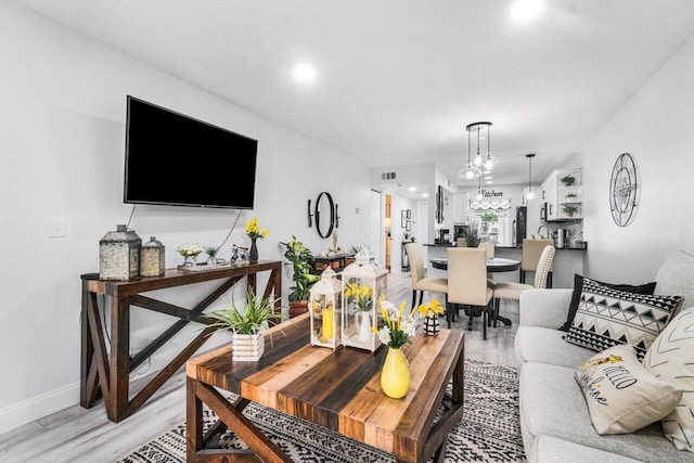 living room with light hardwood / wood-style flooring and an inviting chandelier