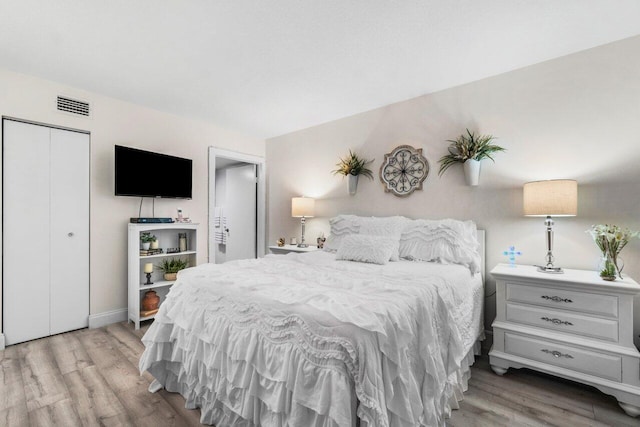 bedroom with light hardwood / wood-style floors and a closet