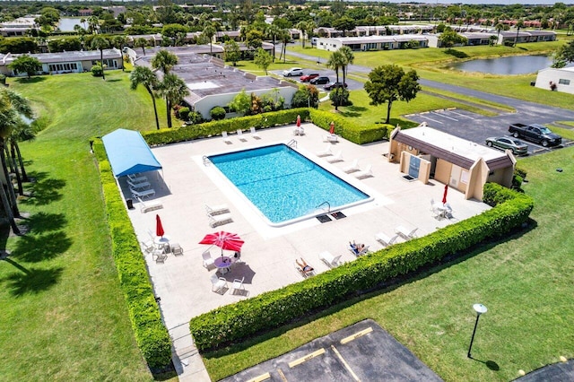 view of swimming pool with a water view, a patio area, and a lawn