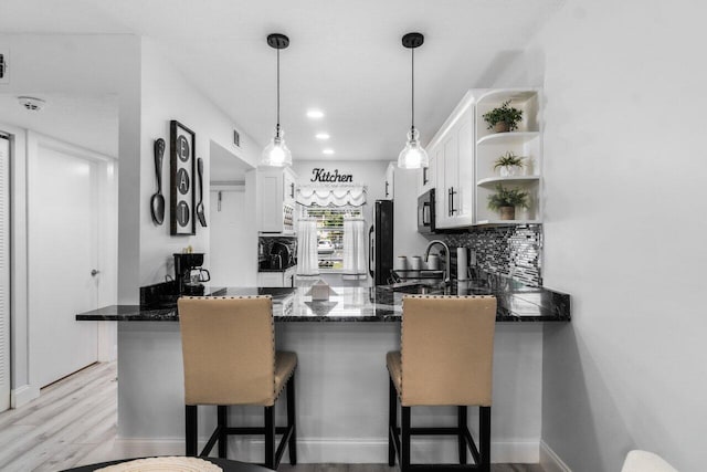 kitchen with a breakfast bar, sink, white cabinetry, light hardwood / wood-style flooring, and kitchen peninsula