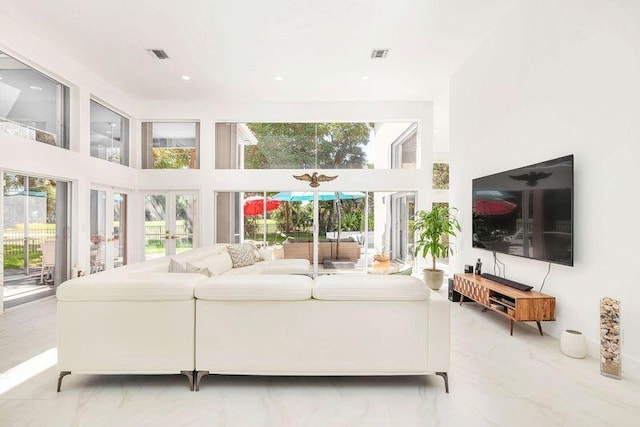 living room with french doors, plenty of natural light, a towering ceiling, and a chandelier