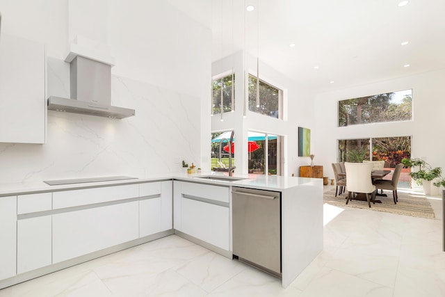 kitchen with stainless steel dishwasher, a towering ceiling, sink, wall chimney exhaust hood, and black electric cooktop