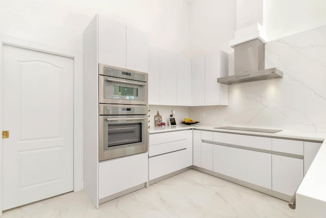 kitchen featuring wall chimney exhaust hood, white cabinetry, black electric stovetop, double oven, and decorative backsplash