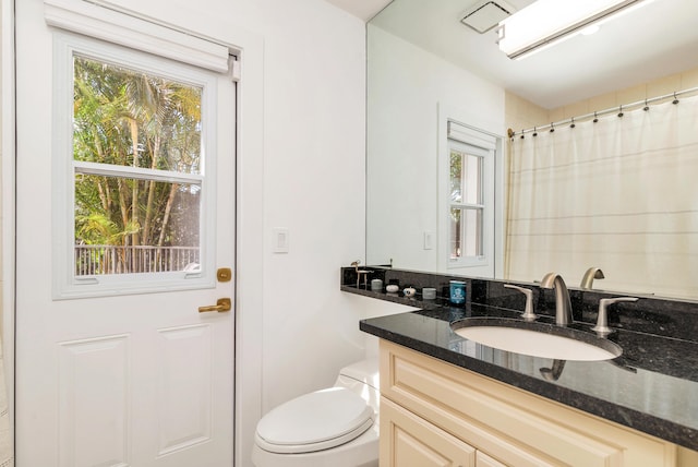 bathroom with toilet, vanity, and walk in shower