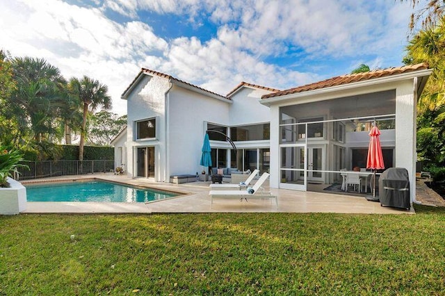 back of property with a patio area, a fenced in pool, and a lawn