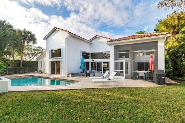 rear view of property with a fenced in pool, a patio area, a sunroom, and a lawn