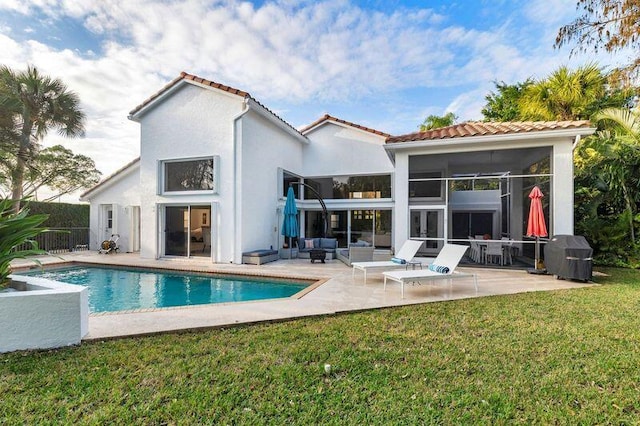 back of house featuring an outdoor living space, a patio area, a sunroom, and a lawn